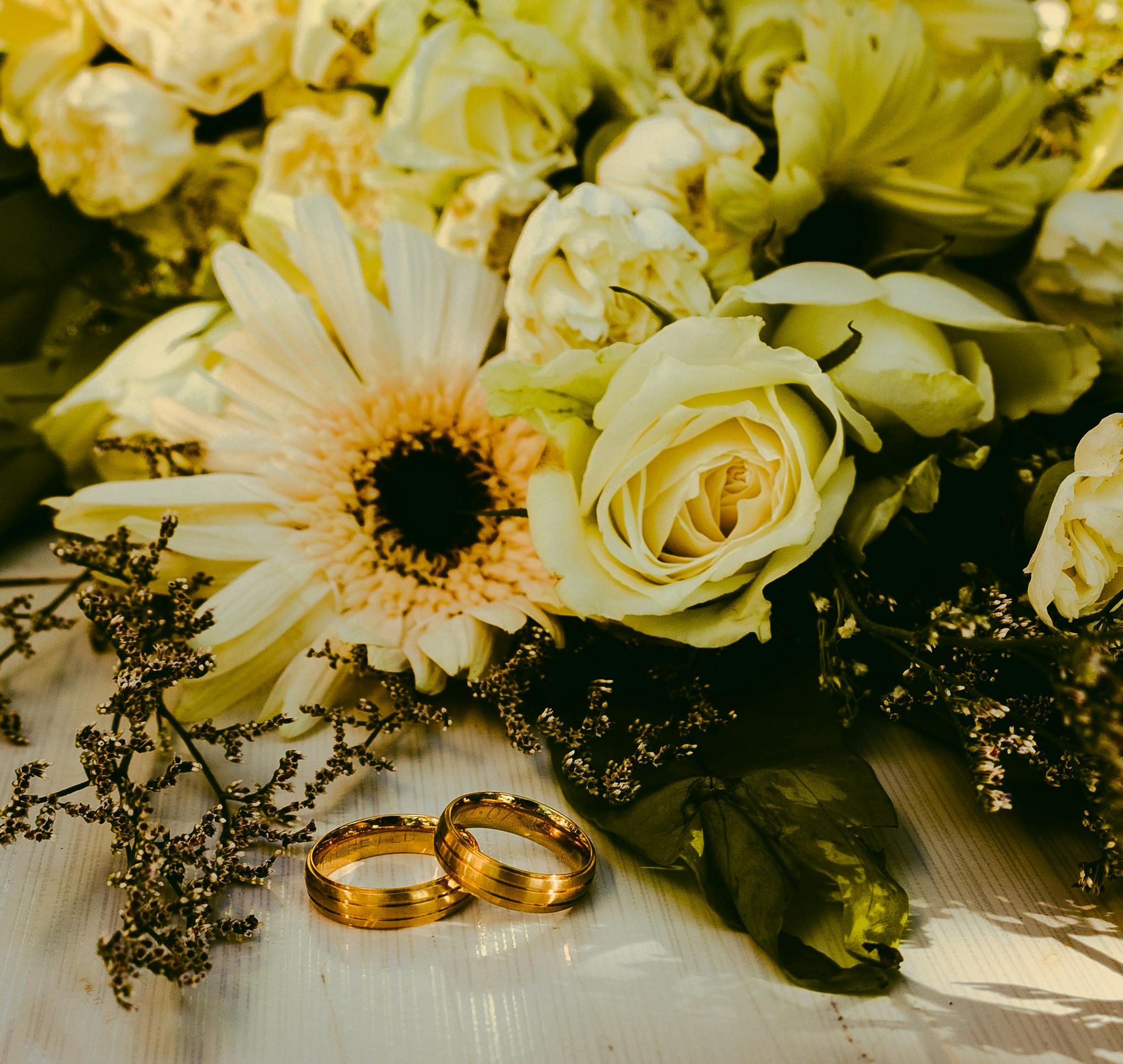 Golden wedding rings with a bouquet of white roses, perfect elegance.