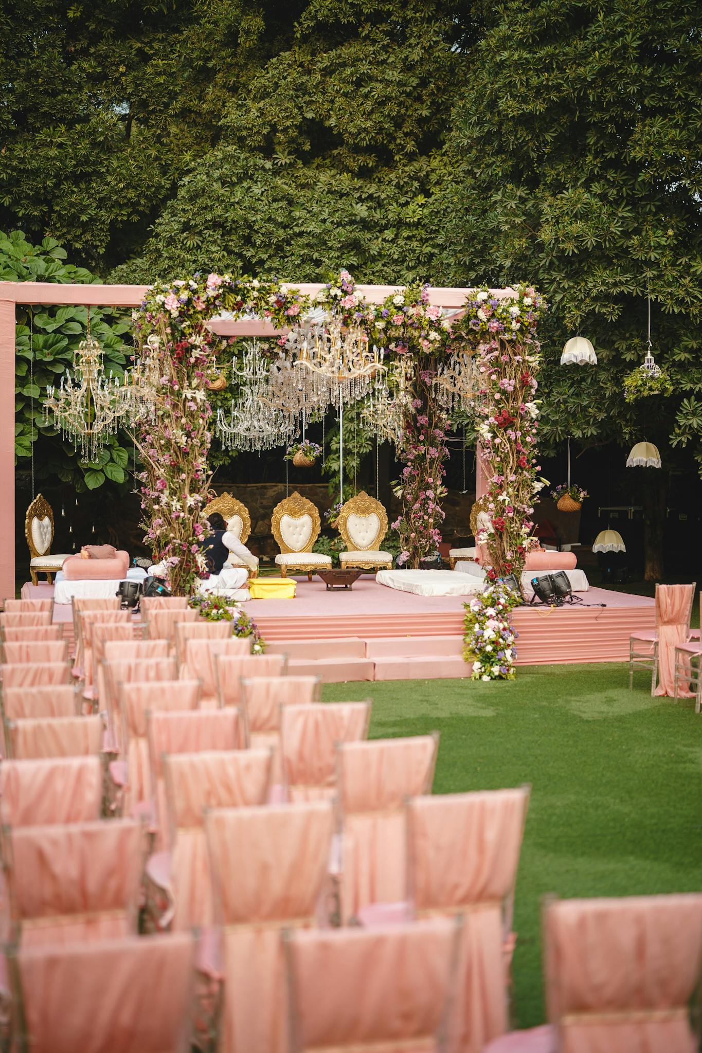 Romantic outdoor wedding ceremony with floral arches and elegant seating on a sunny day.